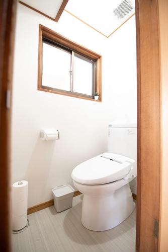 a bathroom with a white toilet and a window at Kaze Box in Kasaoka