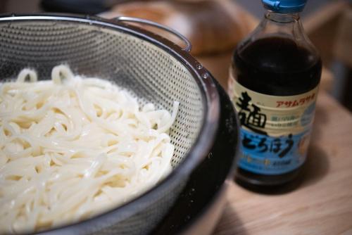 a bowl of noodles and a bottle of sauce at Kaze Box in Kasaoka