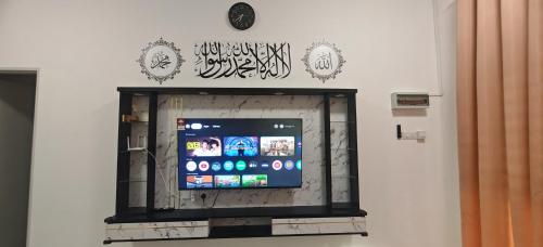 a flat screen tv on a wall with writing on it at ZARI Homestay Kamunting in Gua Sai