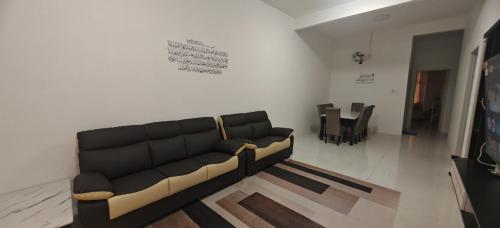 a living room with a black couch and a table at ZARI Homestay Kamunting in Gua Sai