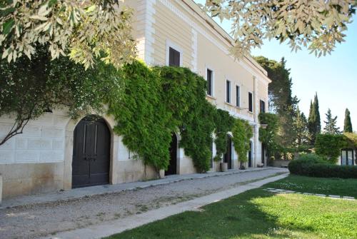 an ivy covered building with a black door and a street at Cefalicchio B&B in Canosa di Puglia