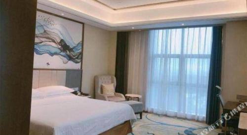 a bedroom with a bed and a chair and a window at Venus Royal Hotel Nanning East High-Speed Railway Station in Nanning