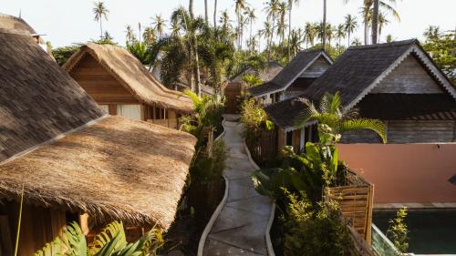 Un grupo de casas con techos de paja y un camino en Coral Drift Resort & Villas Gili Air, en Gili Air
