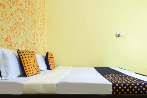 a bedroom with a bed with yellow and black pillows at SPOT ON Saini Guest House in Roorkee