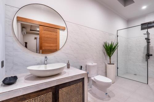 a bathroom with a sink and a mirror and a toilet at Villa Gaia Canggu in Canggu