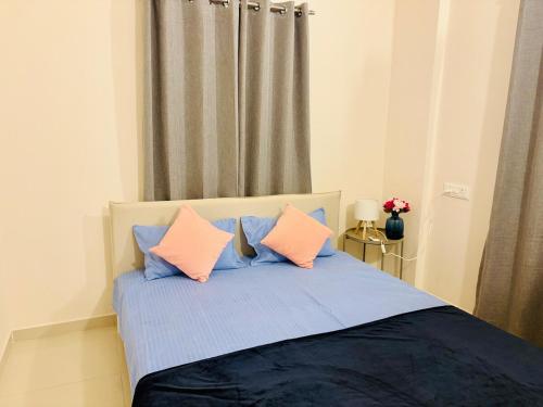 a bedroom with a bed with pink and blue pillows at Peaceful AC 1BHK Near Forest Reserve Hadapsar in Pune