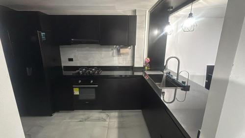 a black kitchen with a stove and a sink at Casa Maola in Neiva