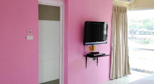 a tv on a pink wall in a bedroom at C2 Residence Hotel in Lampang