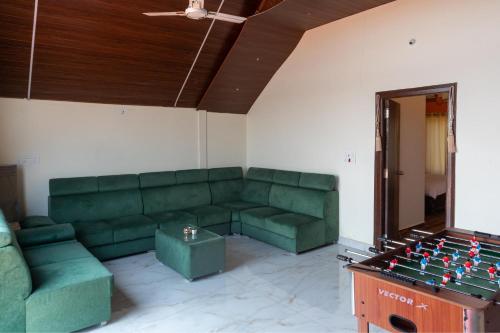 a living room with a green couch and a table at Blissora Retreat Villa by StayJade-Pvt Pool-Lawn in Venkatāpur
