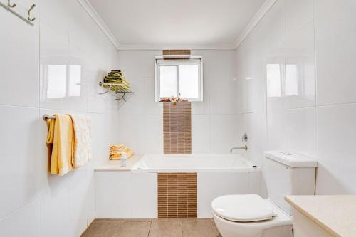 y baño blanco con aseo y bañera. en Rivergrande Apartment, en Innisfail