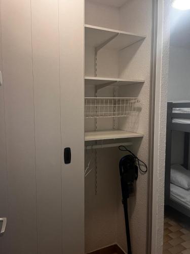 einen Schrank mit einer weißen Tür und einem Regal in der Unterkunft Studio avec vue sur le port in Mauguio