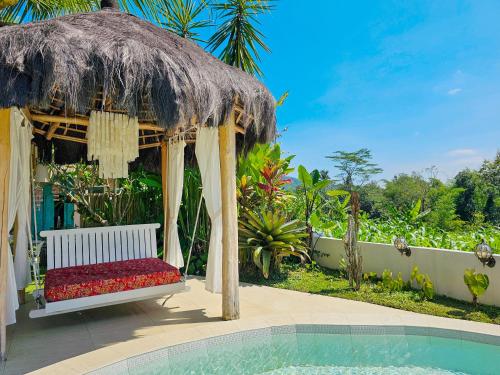 a gazebo with a bench next to a swimming pool at Janur Bungalow in Borobudur