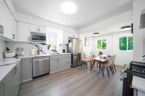 a kitchen with white cabinets and a table with chairs at Cozy four bedroom House in Vancouver West in Vancouver