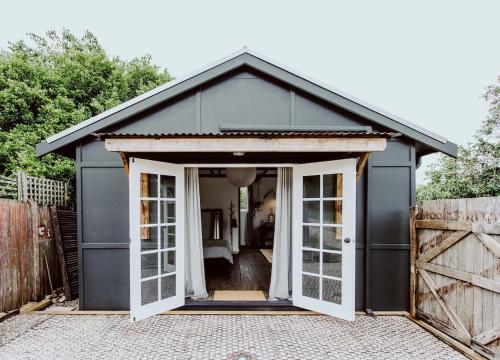 a black garage with doors open on a driveway at The Barn Bellingen in Bellingen