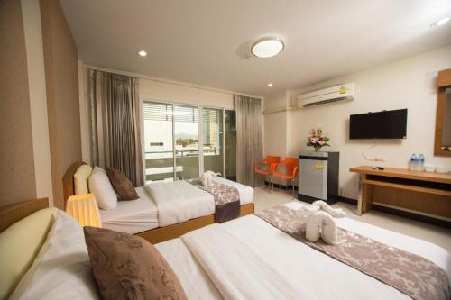 a hotel room with two beds and a television at TK Mansion in Ban Kohong