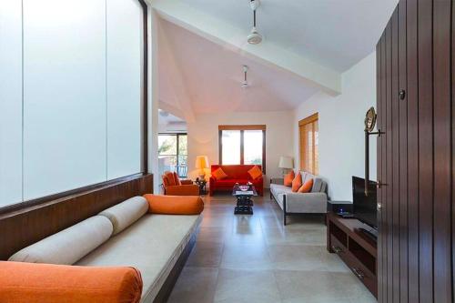 a living room with a long couch and a television at 3Tropical Woods 4BR Villa in North Goa PoolCook in Bardez