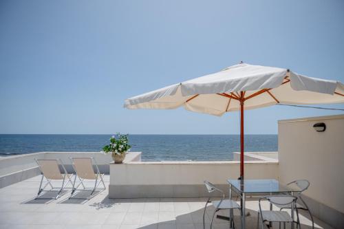 a patio with chairs and an umbrella and the ocean at Rosa Dei Venti in Calabernardo