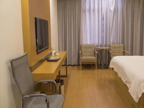 a hotel room with a bed and a desk with a television at GreenTree Inn Qingdao Jiaozhou Jiaoping Road Express Hotel in Qingdao