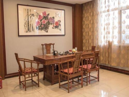 a dining room with a wooden table and chairs at GreenTree Inn Qingdao Jiaozhou Jiaoping Road Express Hotel in Qingdao