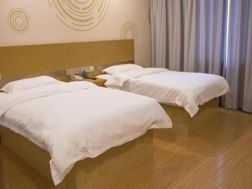 two beds in a hotel room with white sheets at GreenTree Inn Qingdao Jiaozhou Jiaoping Road Express Hotel in Qingdao