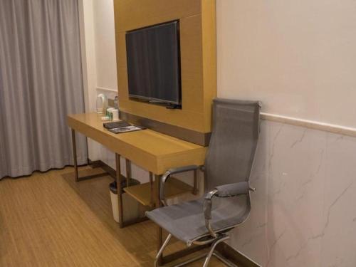a desk with a television and a chair in a room at GreenTree Inn Qingdao Jiaozhou Jiaoping Road Express Hotel in Qingdao
