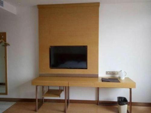 a flat screen tv sitting on top of a wooden table at GreenTree Inn Qingdao Jiaozhou Jiaoping Road Express Hotel in Qingdao
