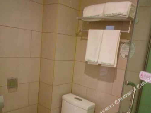 a small bathroom with a toilet and towels at GreenTree Inn Qingdao Jiaozhou Jiaoping Road Express Hotel in Qingdao