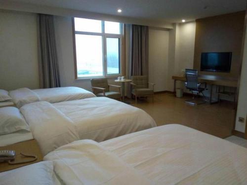 a hotel room with four beds and a television at GreenTree Inn Qingdao Jiaozhou Jiaoping Road Express Hotel in Qingdao