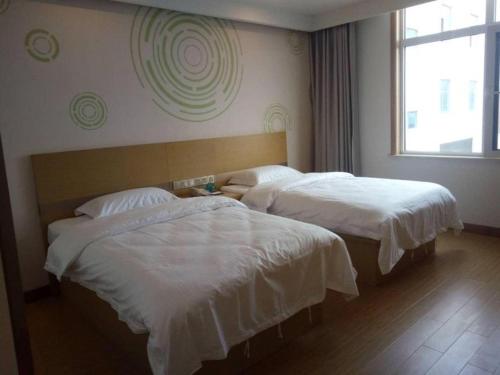 two beds in a hotel room with white sheets at GreenTree Inn Qingdao Jiaozhou Jiaoping Road Express Hotel in Qingdao