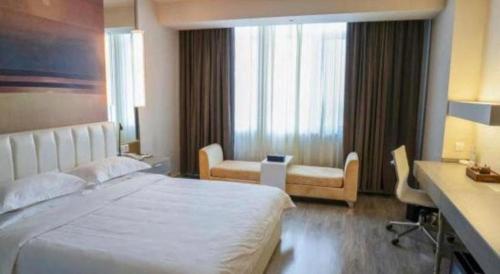 a hotel room with a large bed and a desk at Jinjiang Metropolo Hotel - Turpan Administration Center in Turfan