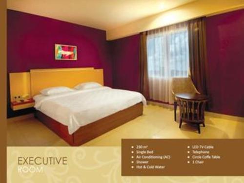 a bedroom with a bed and a table and a window at Borneo Hotel in Pontianak