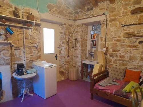 a room with a stone wall with a sink and a couch at Stoneworld in Évdhilos