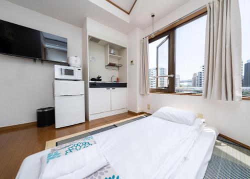 Una pequeña habitación con una cama y un microondas. en 匯金芝浦ビル, en Tokio