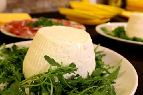 a piece of cheese on a plate with greens on a table at Agriturismo La Casa di Bacco in Agrigento