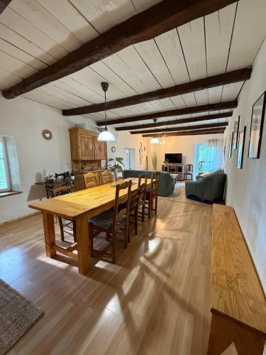 a dining room and living room with a wooden table and chairs at La clé de la forêt in Métairies-Saint-Quirin