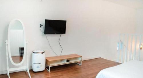 a bedroom with a tv on the wall and a table at All That Water Pension in Gapyeong