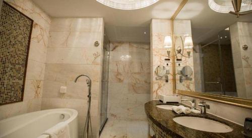 a bathroom with two sinks and a tub and a shower at Fortune International Hotel in Xiawutun