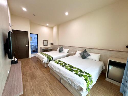 a hotel room with two beds and a flat screen tv at Travel Happiness Homestay in Huxi