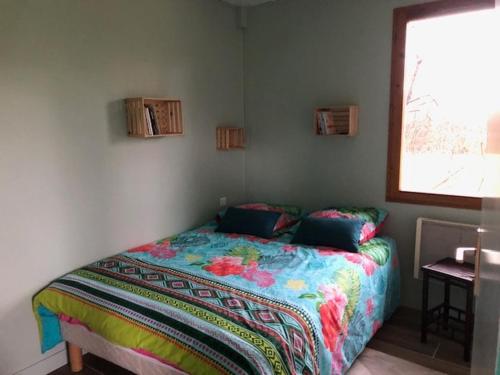 une chambre avec un lit avec une couette colorée et une fenêtre dans l'établissement Petite maisonnette dans les près, à Villerest