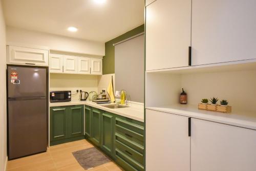 a kitchen with green and white cabinets and a refrigerator at Sunway Grid Loft Suite by Nest Home【Olympic Size Pool】 in Kampong Pendas