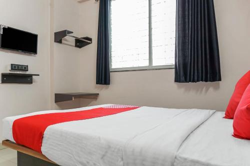 a bedroom with a bed with a red blanket and a window at Hotel O Swagat Lodging in Khadki