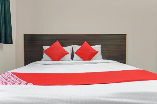 a bed with red and white pillows on it at Hotel O Swagat Lodging in Khadki