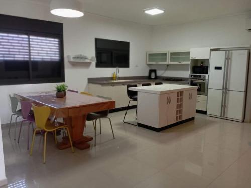 a large kitchen with a wooden table and chairs at Lotus - Vacation in Emek Hama'ayanot in Rewaya