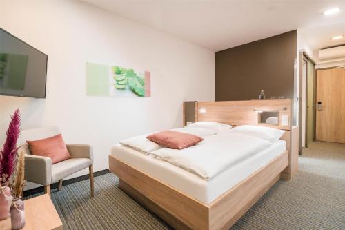 a bedroom with a large bed and a chair at Best Western Plus Kurhotel an der Obermaintherme in Bad Staffelstein