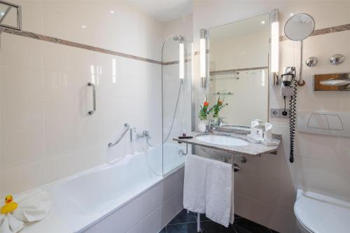 a bathroom with a tub and a sink and a shower at Best Western Plus Kurhotel an der Obermaintherme in Bad Staffelstein