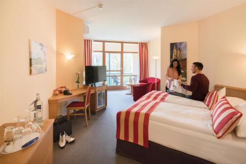 two people sitting on a bed in a hotel room at Best Western Plus Kurhotel an der Obermaintherme in Bad Staffelstein