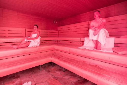 two women are sitting in a red bleachers at Best Western Plus Kurhotel an der Obermaintherme in Bad Staffelstein
