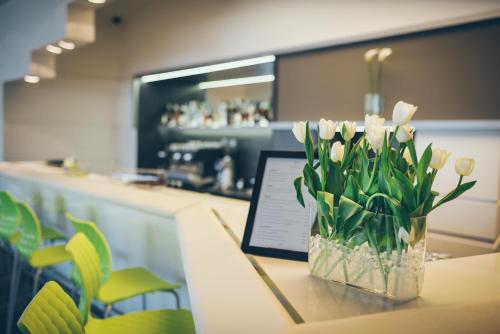 a vase of white flowers on a table with a laptop at Best Western Plus Lakeside Hotel in Székesfehérvár
