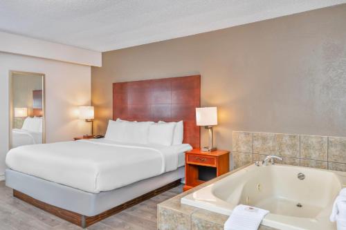 a hotel room with a bed and a bath tub at Comfort Inn & Suites Thousand Islands Harbour District in Gananoque