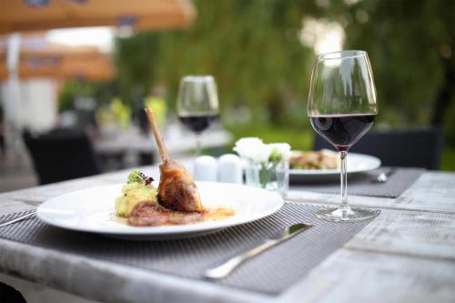 a table with a plate of food and a glass of wine at Best Western Plus Lakeside Hotel in Székesfehérvár
